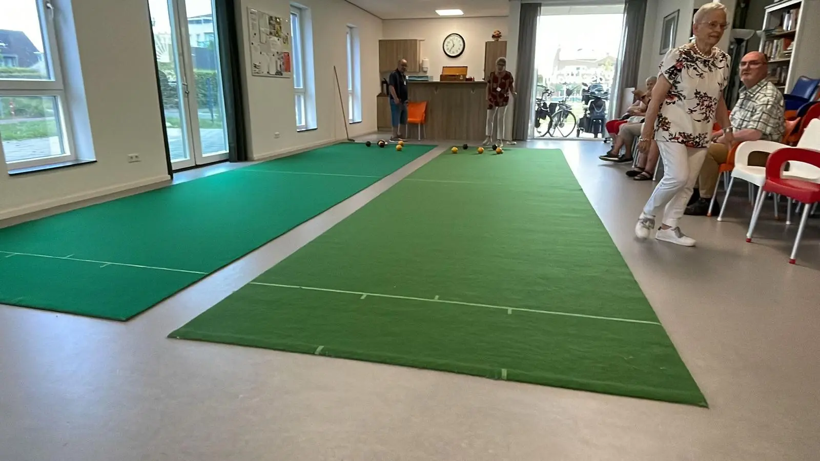 Two green koersbal lanes in use inside a community room